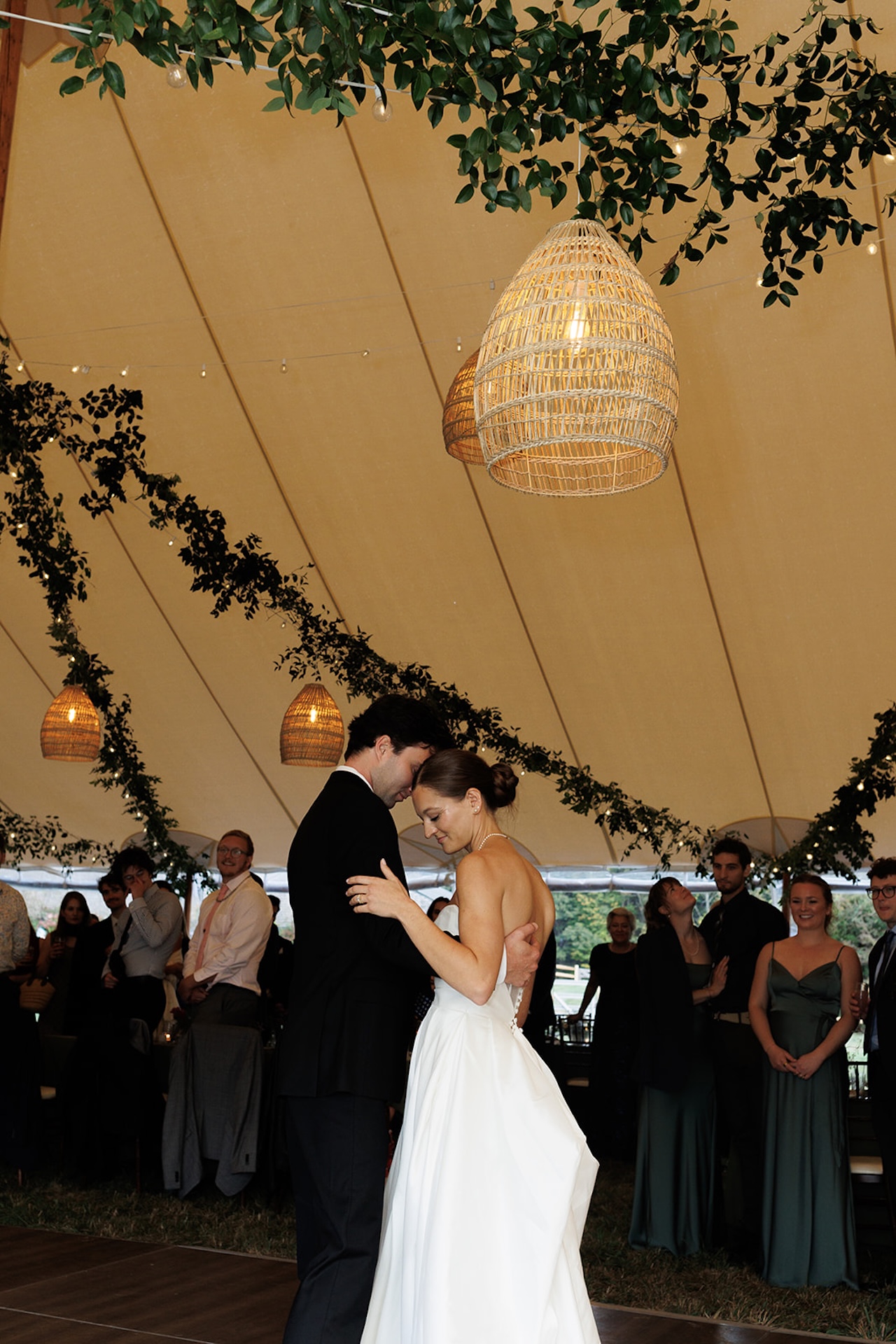 The bride and groom enjoy their first dance under a greenery-draped tent at their Wedding in Maine celebration.