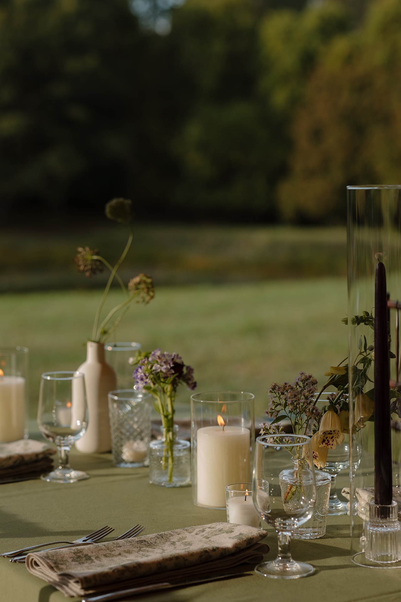 A softly lit reception table setup with candles, glassware, and petite florals at a Wedding in Maine.