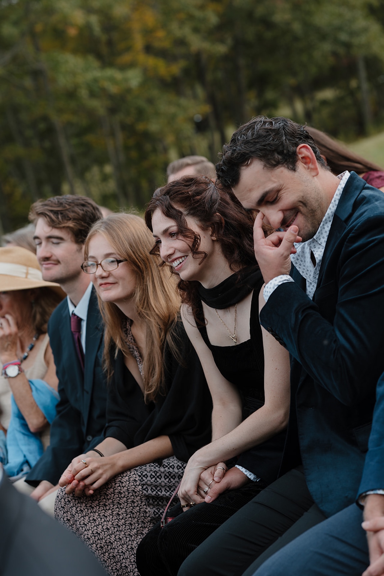 Guests smile, laugh, and hold hands while watching the ceremony at a Wedding in Maine.