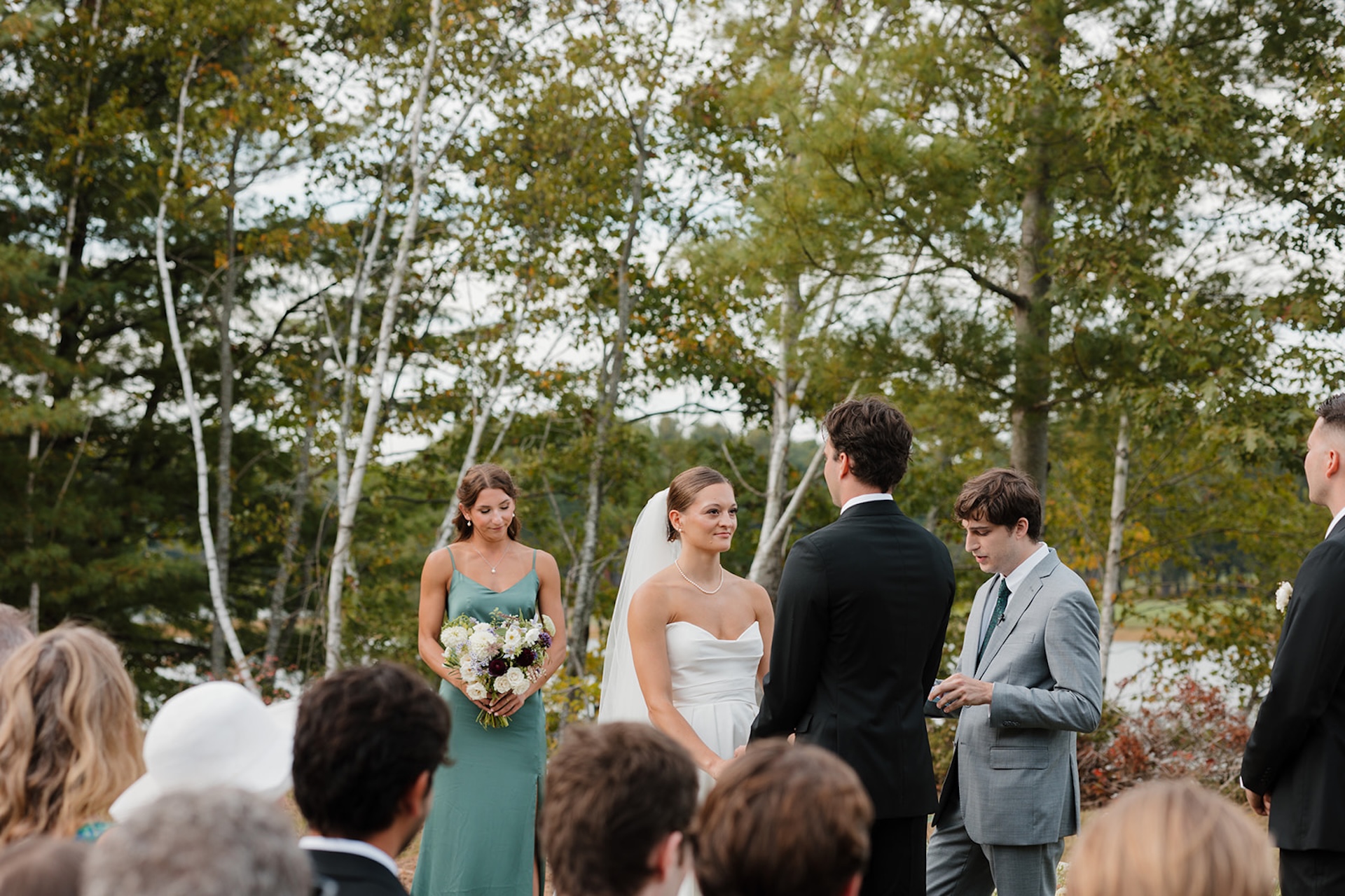 A heartfelt outdoor ceremony moment during a lakeside Wedding in Maine with guests seated behind them.