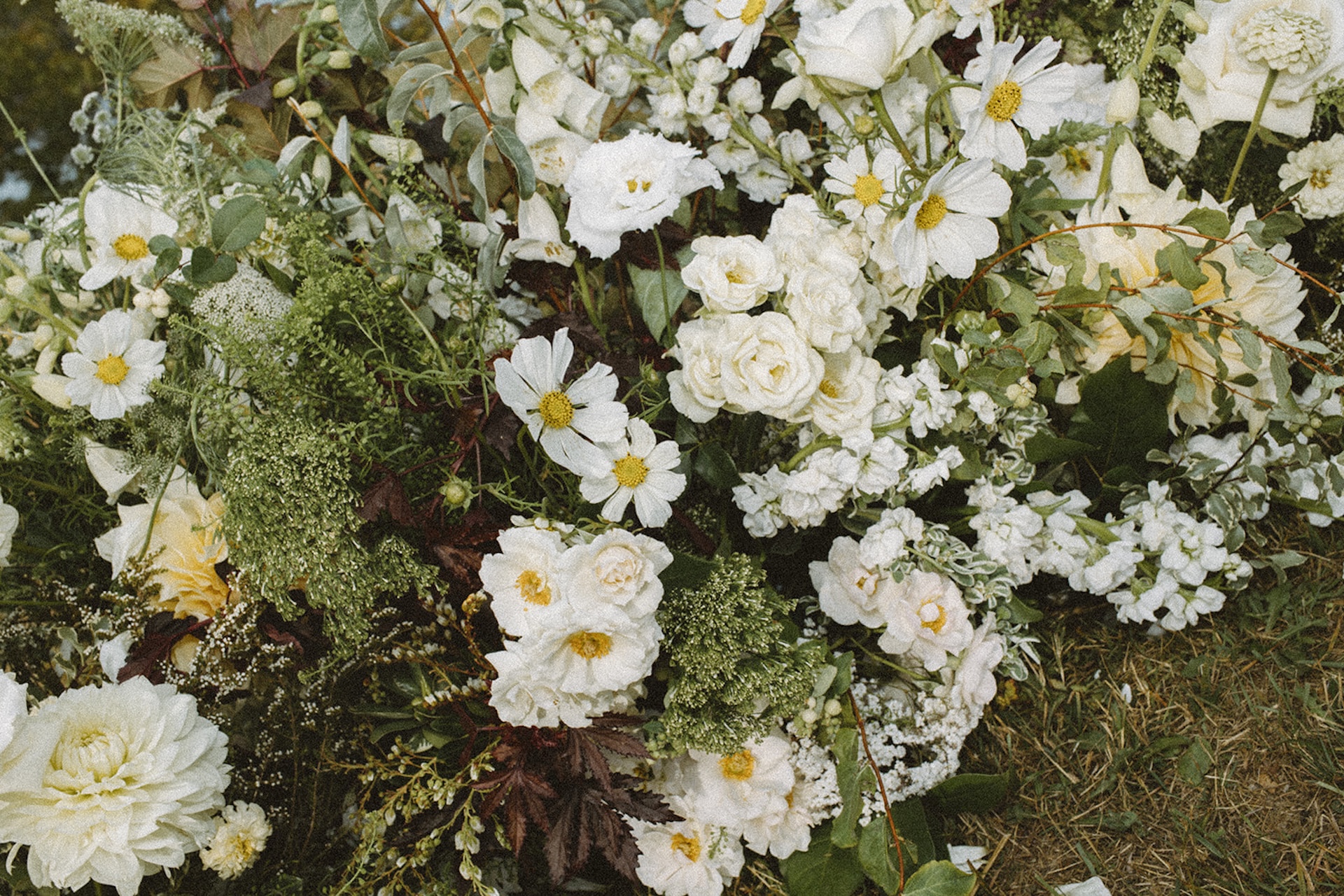 Lush garden-style floral arrangement full of white blooms and greenery from a Wedding in Maine.