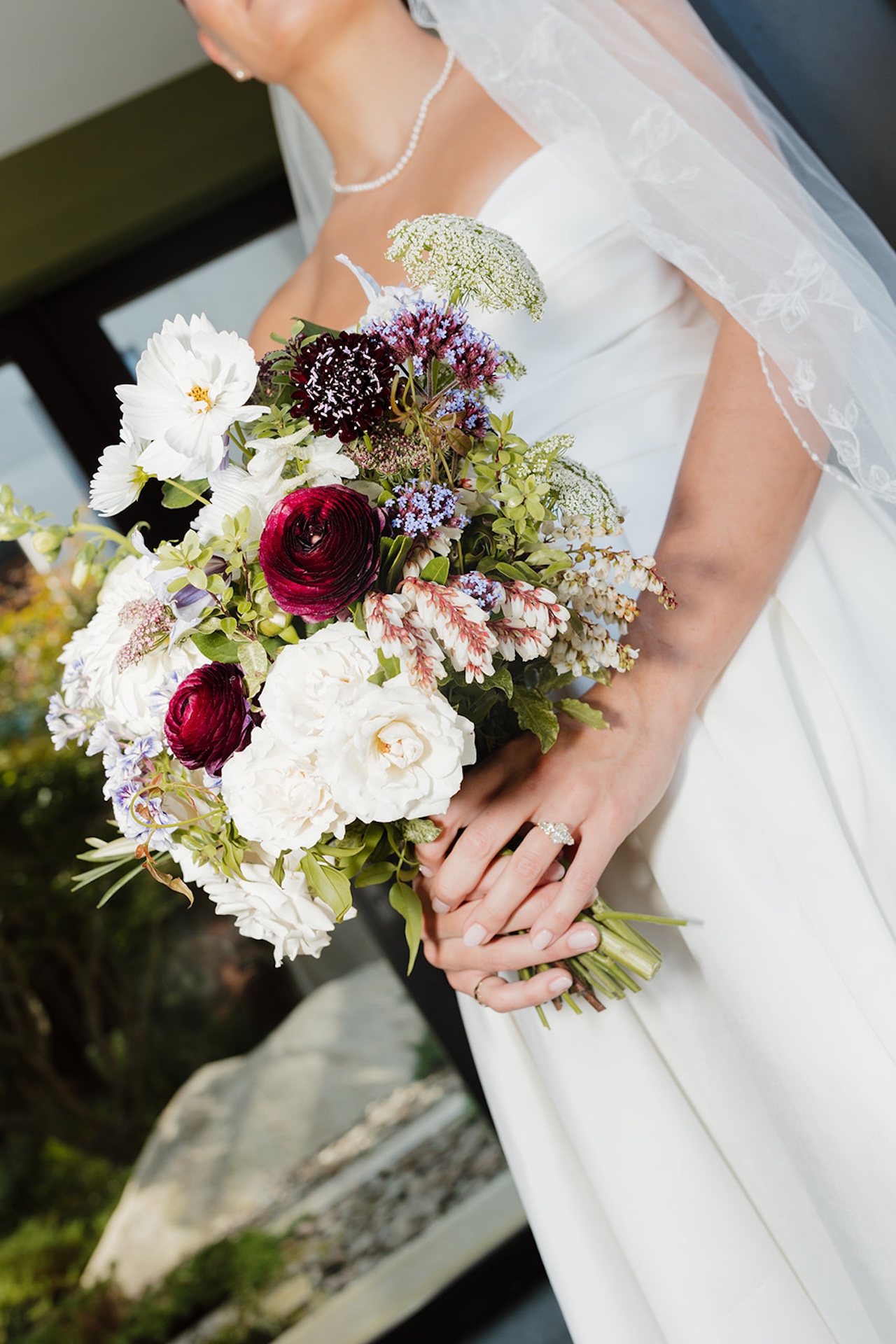 Close-up of the bride holding a lush bouquet of bold and white blooms before her Wedding in Maine ceremony.