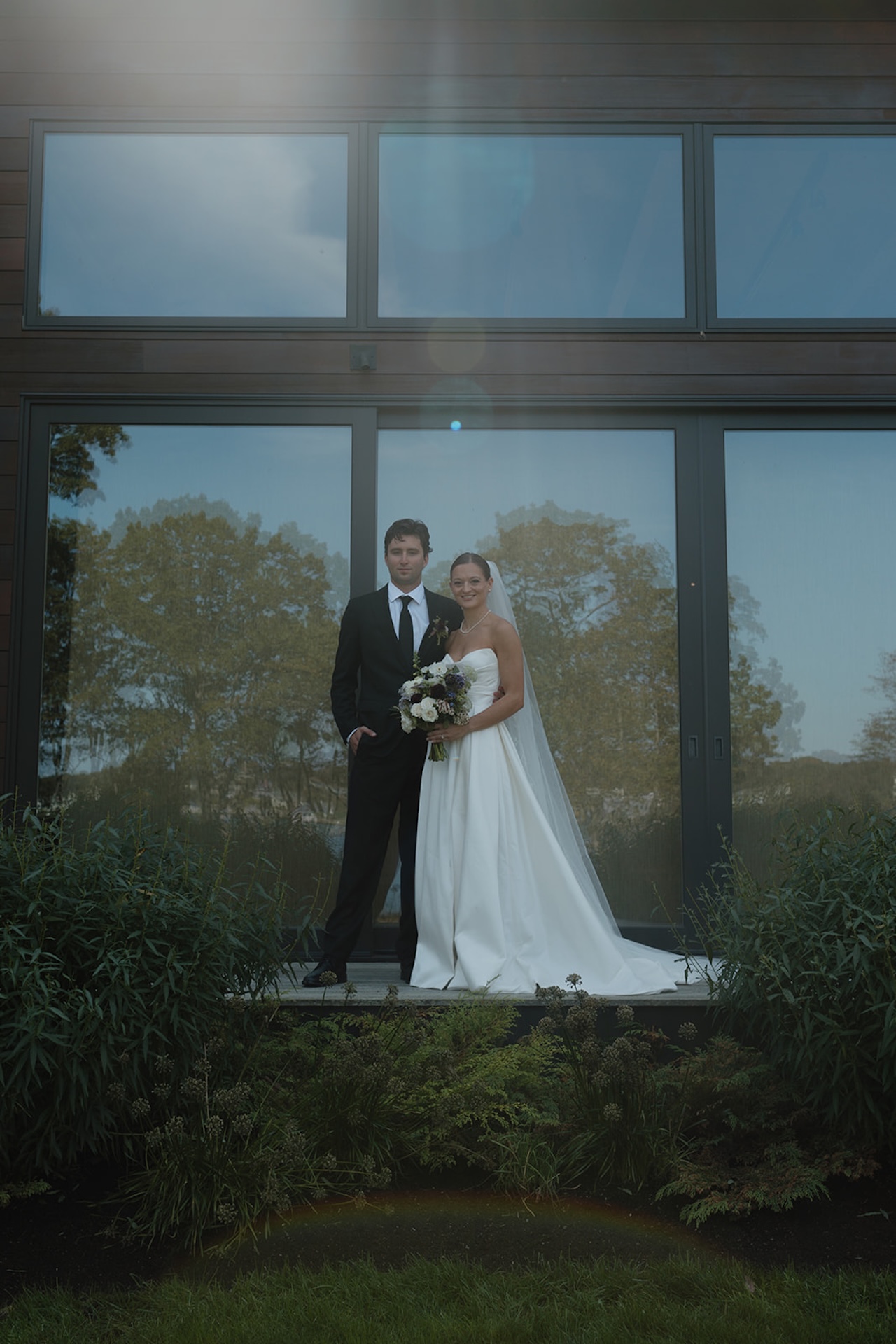 Black-and-white close-up of the bride and groom kissing beneath her veil.