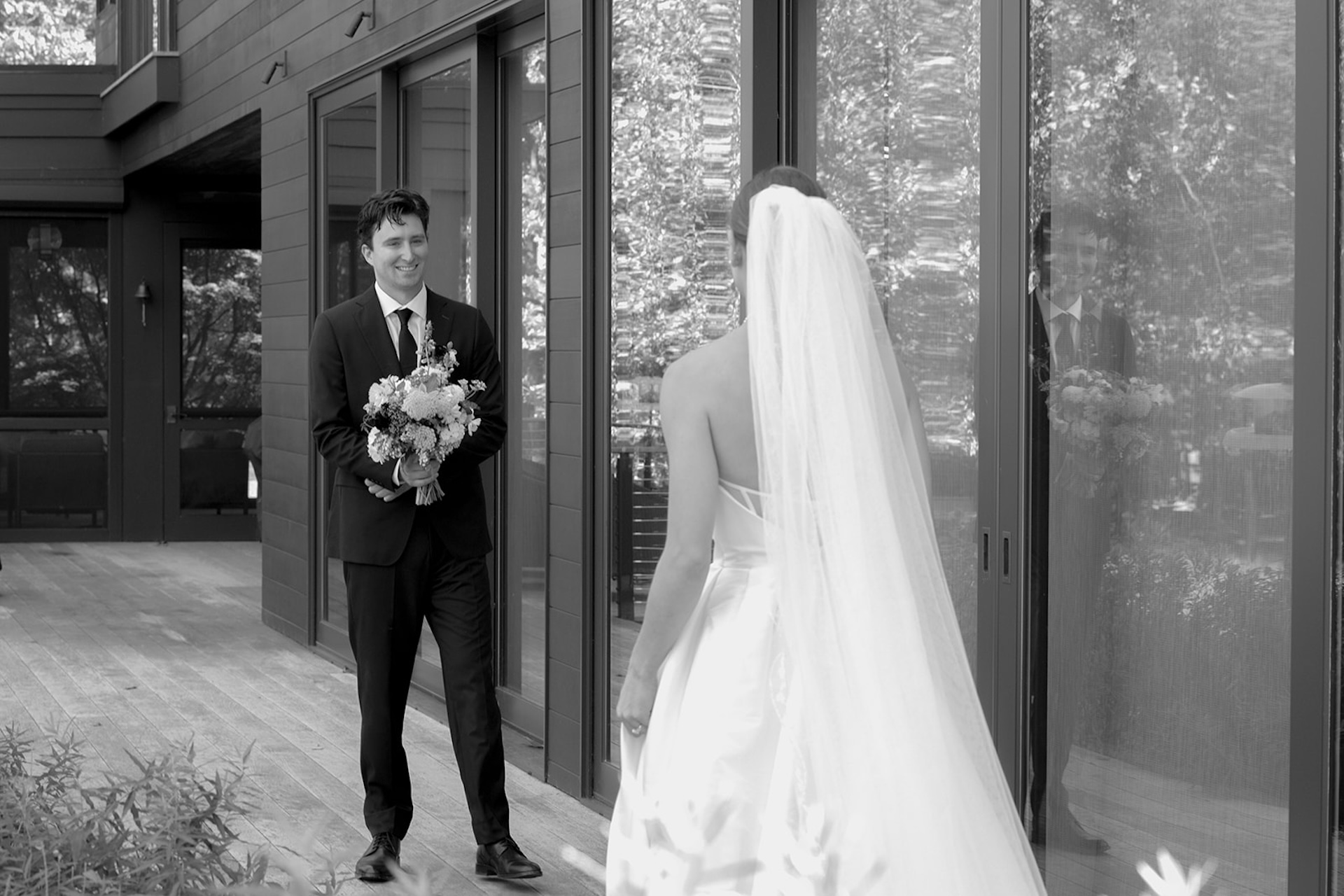 Black-and-white first look moment as the groom smiles, walking toward the bride outside before their Wedding in Maine.