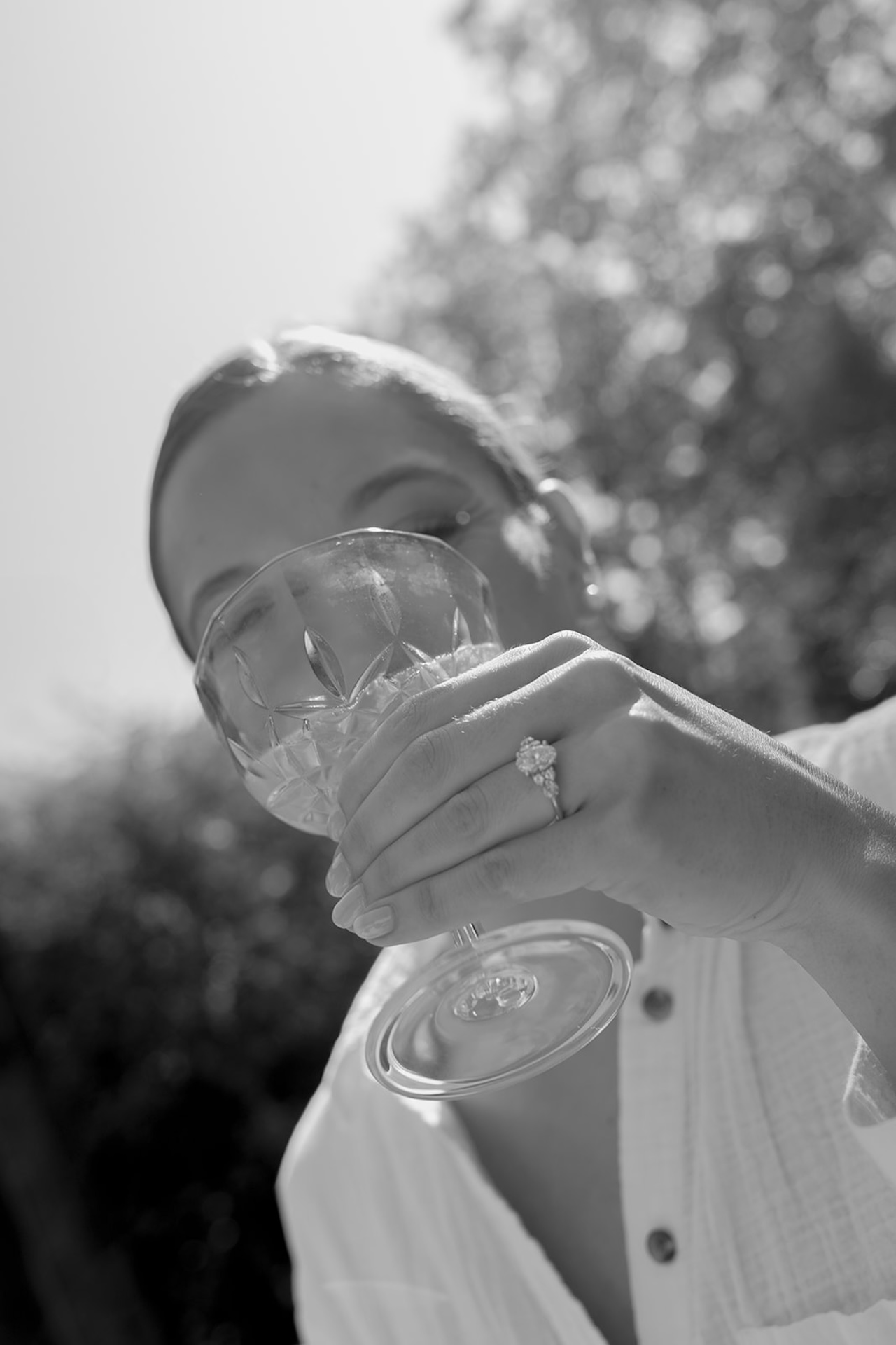 Close-up black-and-white shot of the bride sipping from a crystal coupe glass, her ring in focus at a Wedding in Maine.