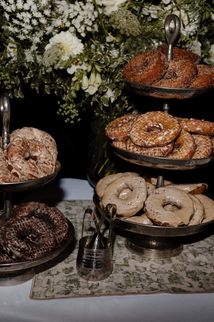 Tiered trays of glazed donuts displayed as a late-night dessert option at their Wedding in Maine reception.