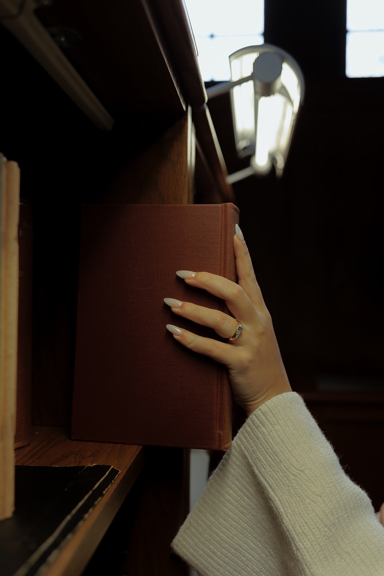 Close-up engagement portrait of a couple browsing books together in a library, creating intimate Engagement Photo Session Ideas with warm, cinematic light.