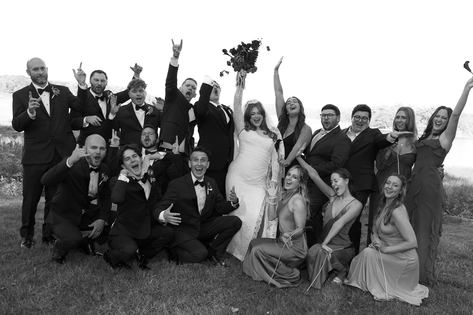 A black and white photo at a Destination Wedding in Maine of the wedding party and bride and groom celebrating around the couple.