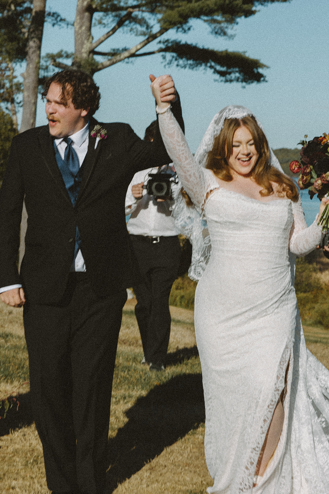 Joyful recessional moment during a Destination Wedding in Maine as the bride and groom walk back down the aisle celebrating with raised hands