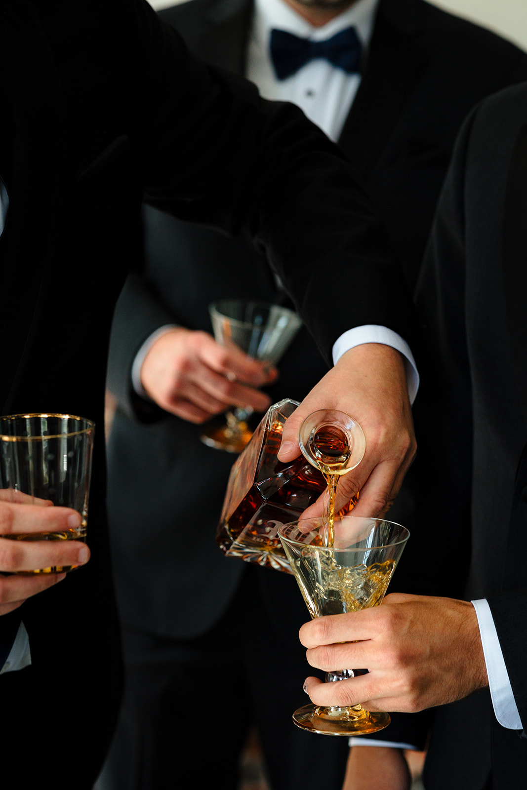 The groom and groomsmen getting ready for a Destination wedding in Maine while pouring glasses of whiskey for everyone.