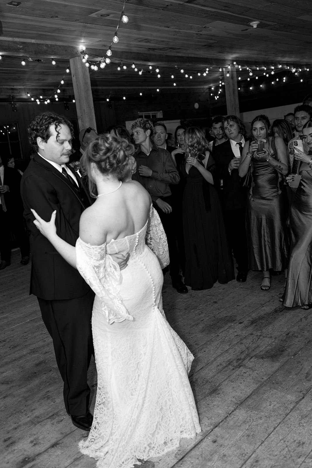 Romantic first dance under glowing string lights during a Destination Wedding in Maine, with soft motion blur and warm, intimate lighting