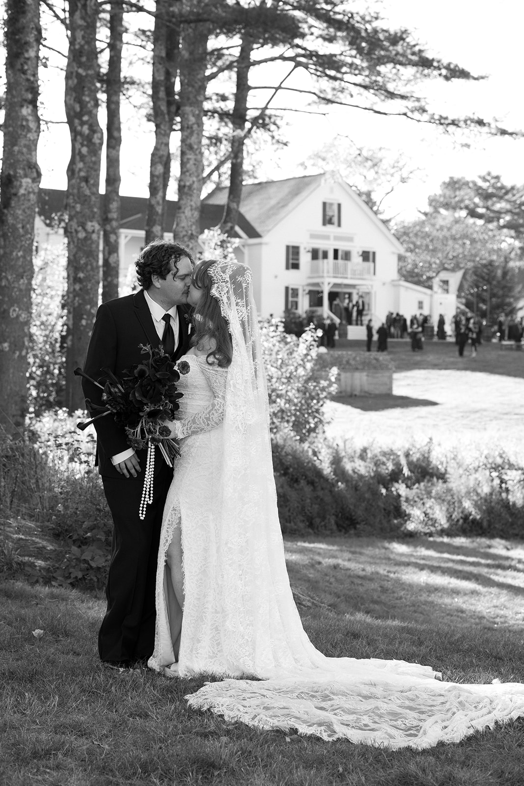 Romantic black and white portrait of the couple kissing on the lawn, with the historic inn softly blurred behind them for a timeless wedding feel
