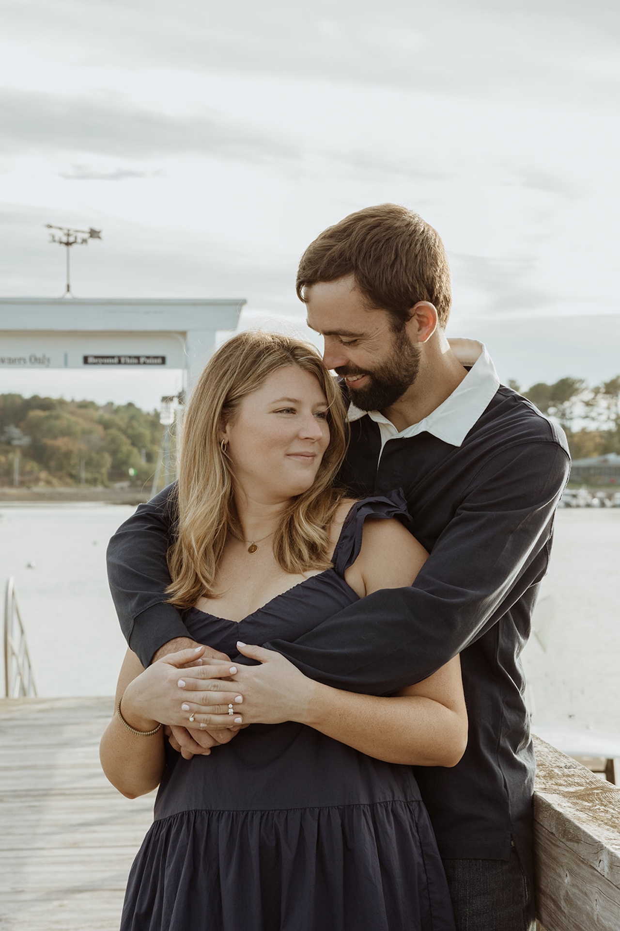 Engagement photo of the couple hugging each other on a dock during their romantic engagement photos at Nubble Lighthouse in York Maine.
