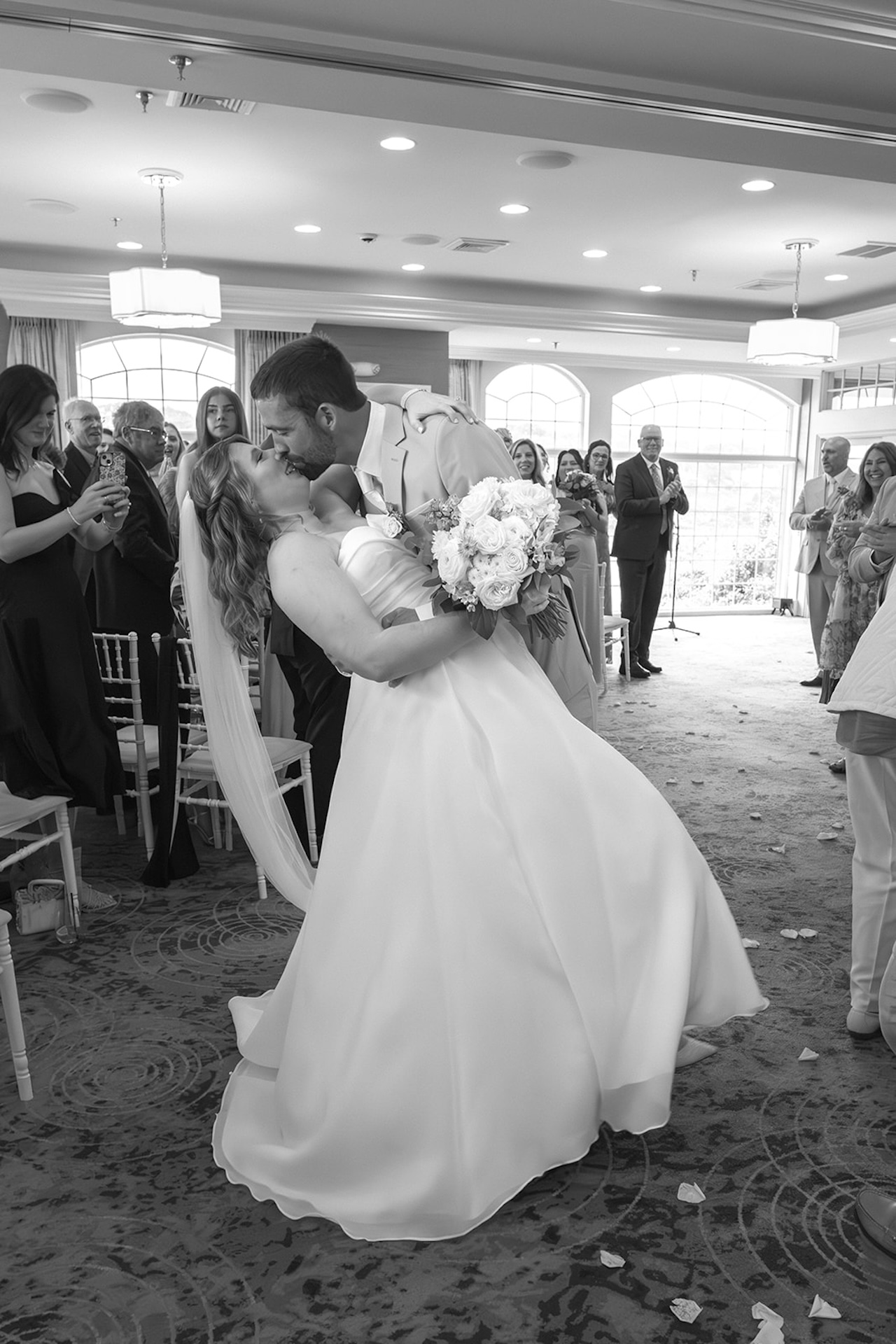 Bride and groom sharing their first kiss at the ceremony surrounded by guests at Stage Neck Inn.