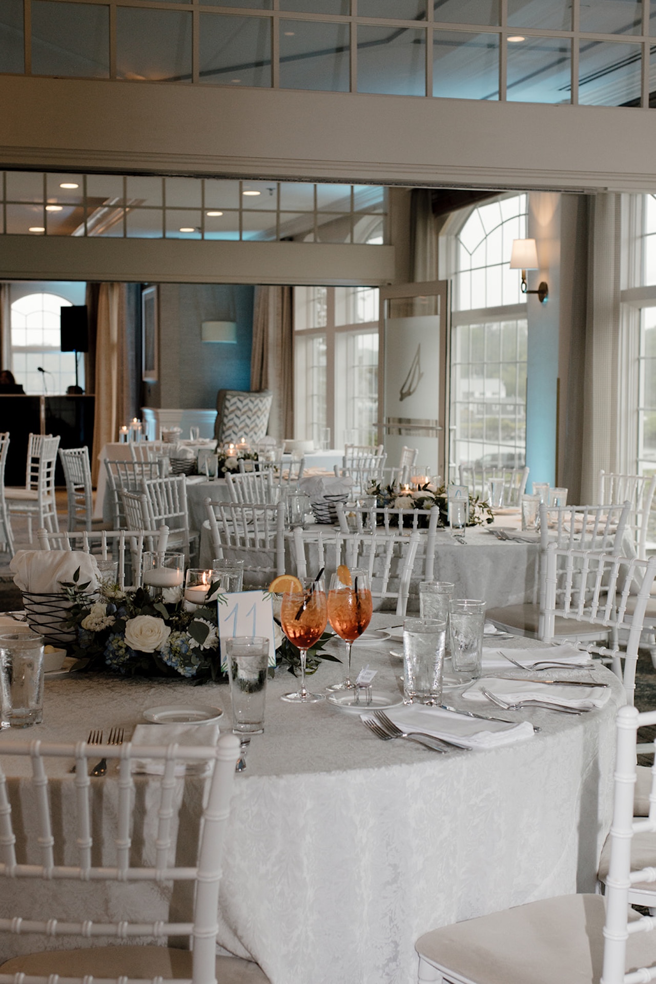 Coastal wedding reception tablescape with white linens, candles, and florals inside Stage Neck Inn.