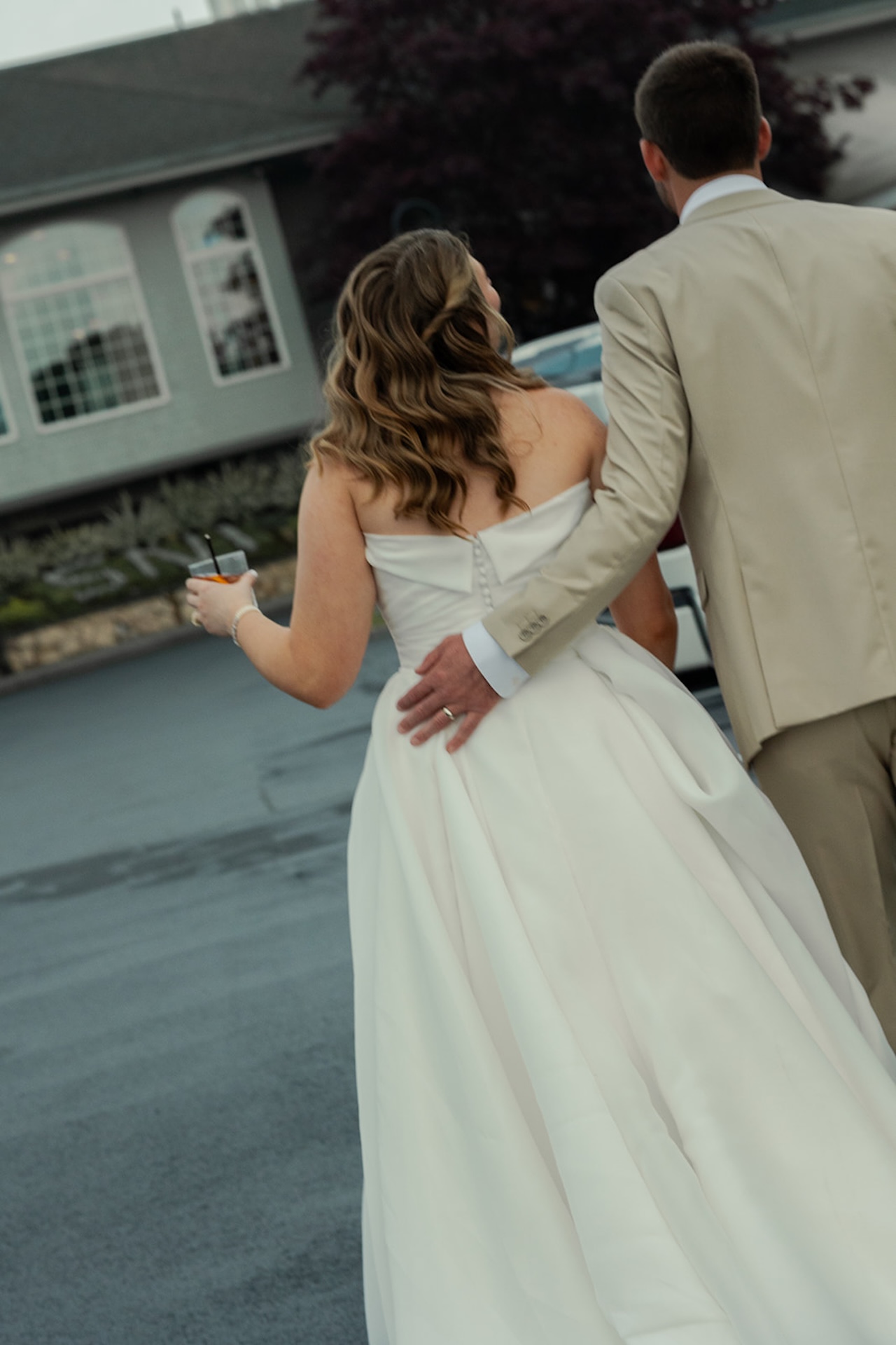 Newlyweds walking arm in arm outside the reception space at Stage Neck Inn holding cocktails.