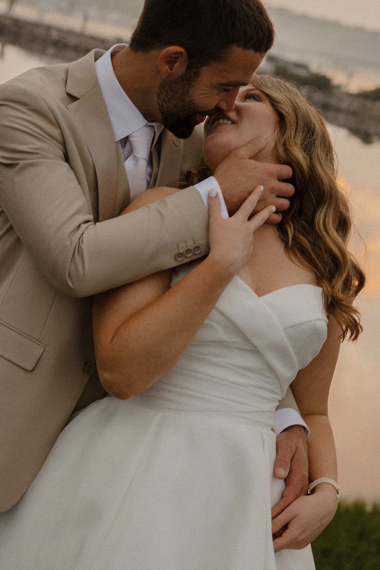 Bride and groom sharing an intimate sunset portrait by the water during their coastal wedding.