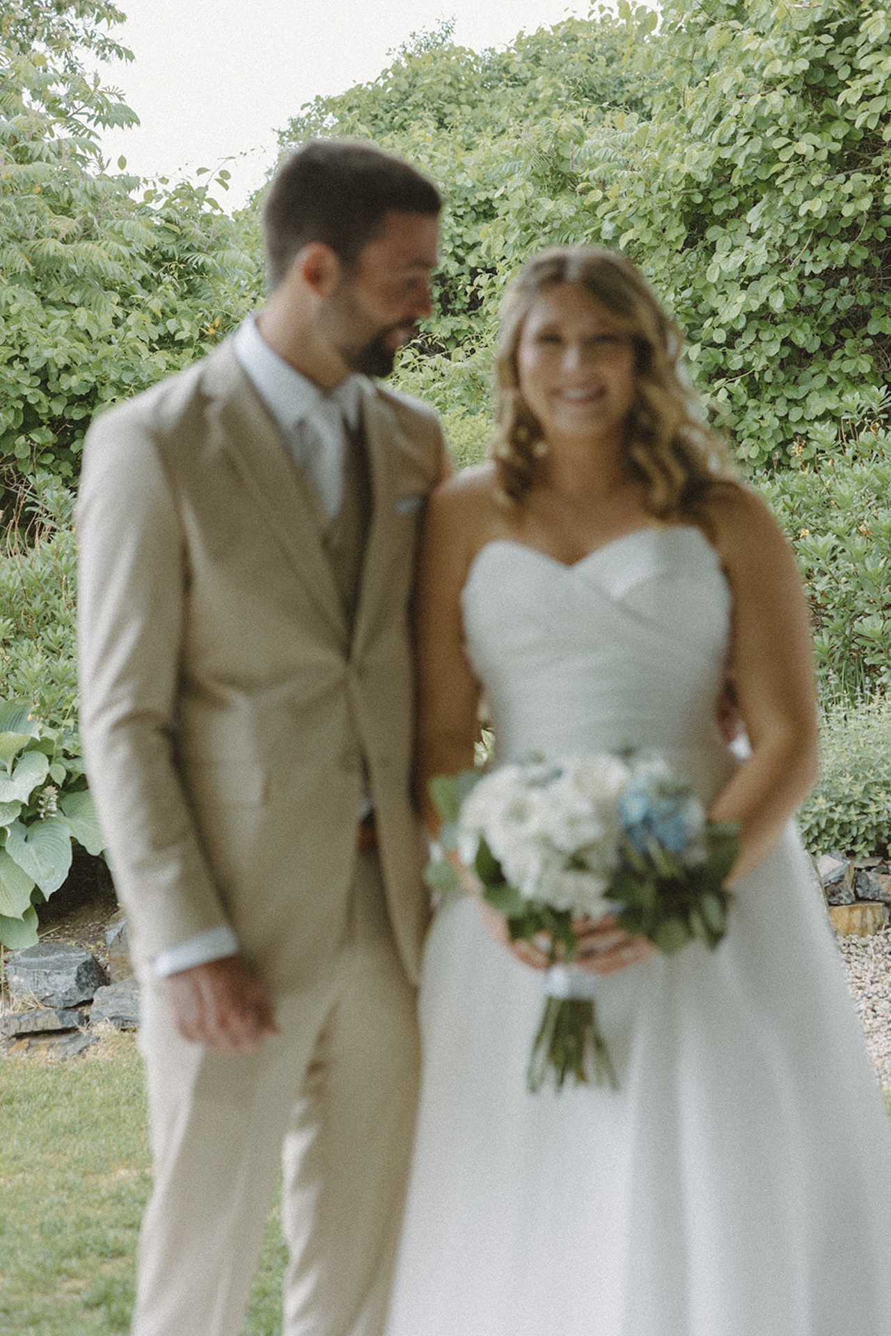 Groom smiling at bride while holding her coastal blue and white wedding bouquet.