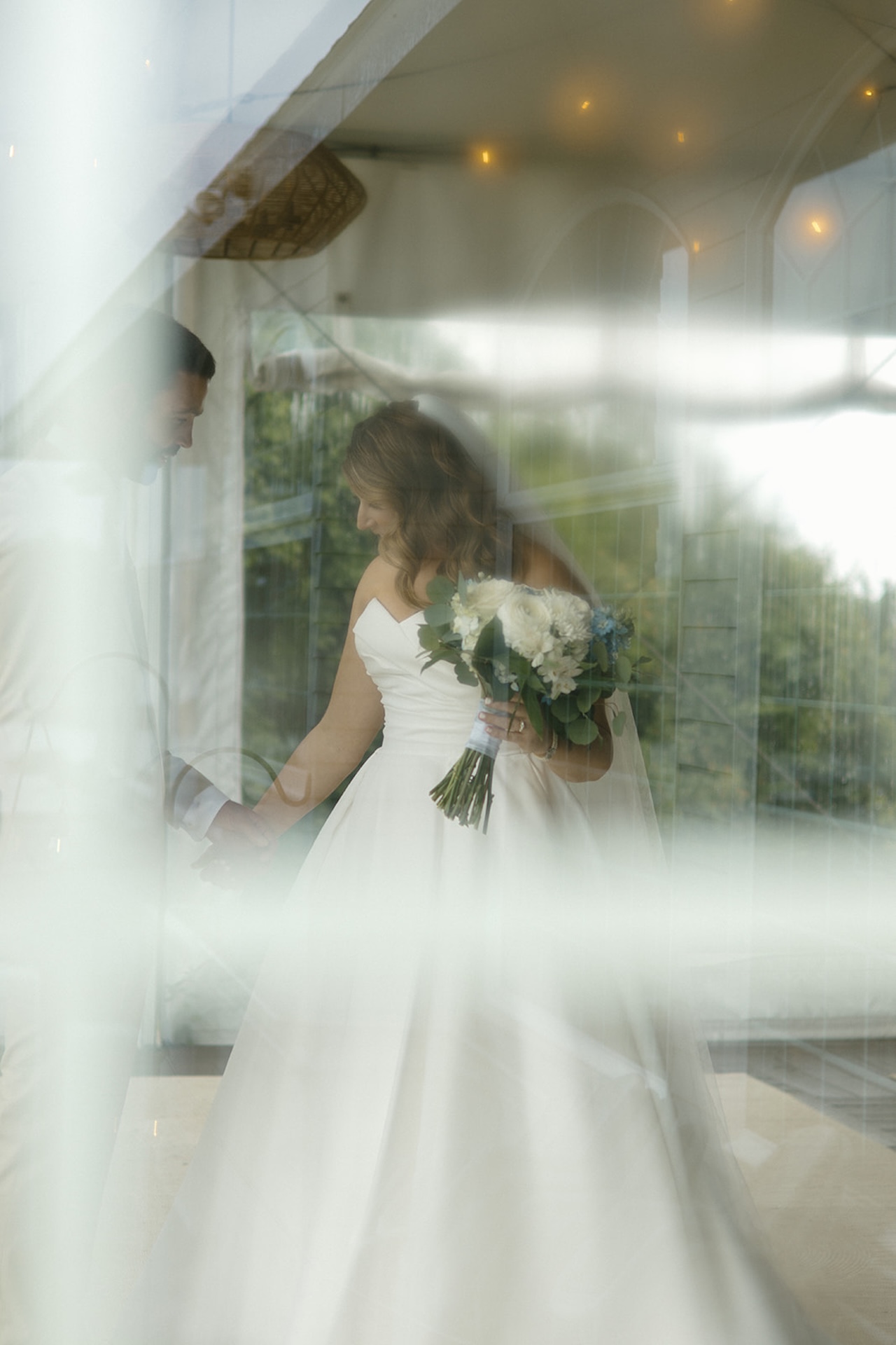 Artistic reflection photo of bride holding bouquet near a window at Stage Neck Inn.