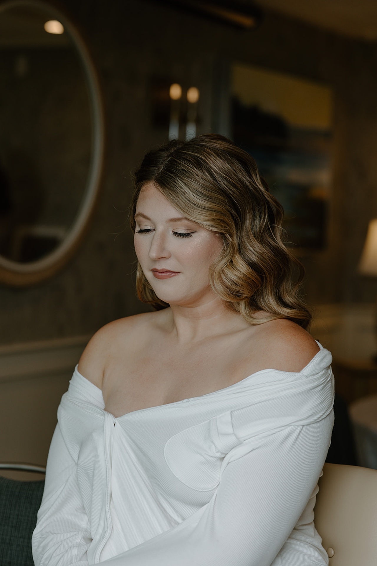 Bride getting her hair and makeup done in soft window light inside a suite at Stage Neck Inn.