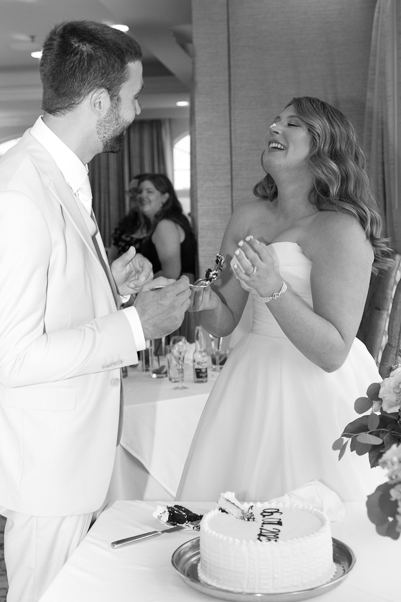 Bride laughing while feeding groom cake during their reception at Stage Neck Inn.