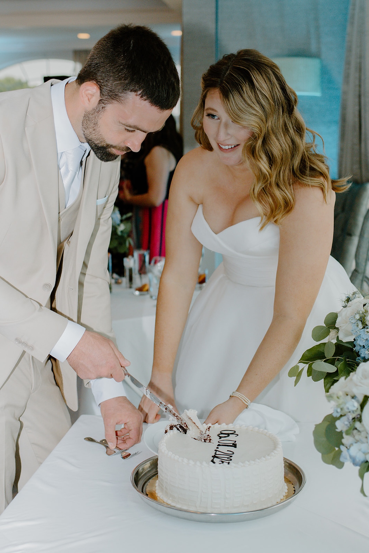 Newlyweds cutting their wedding cake together at their reception celebration.
