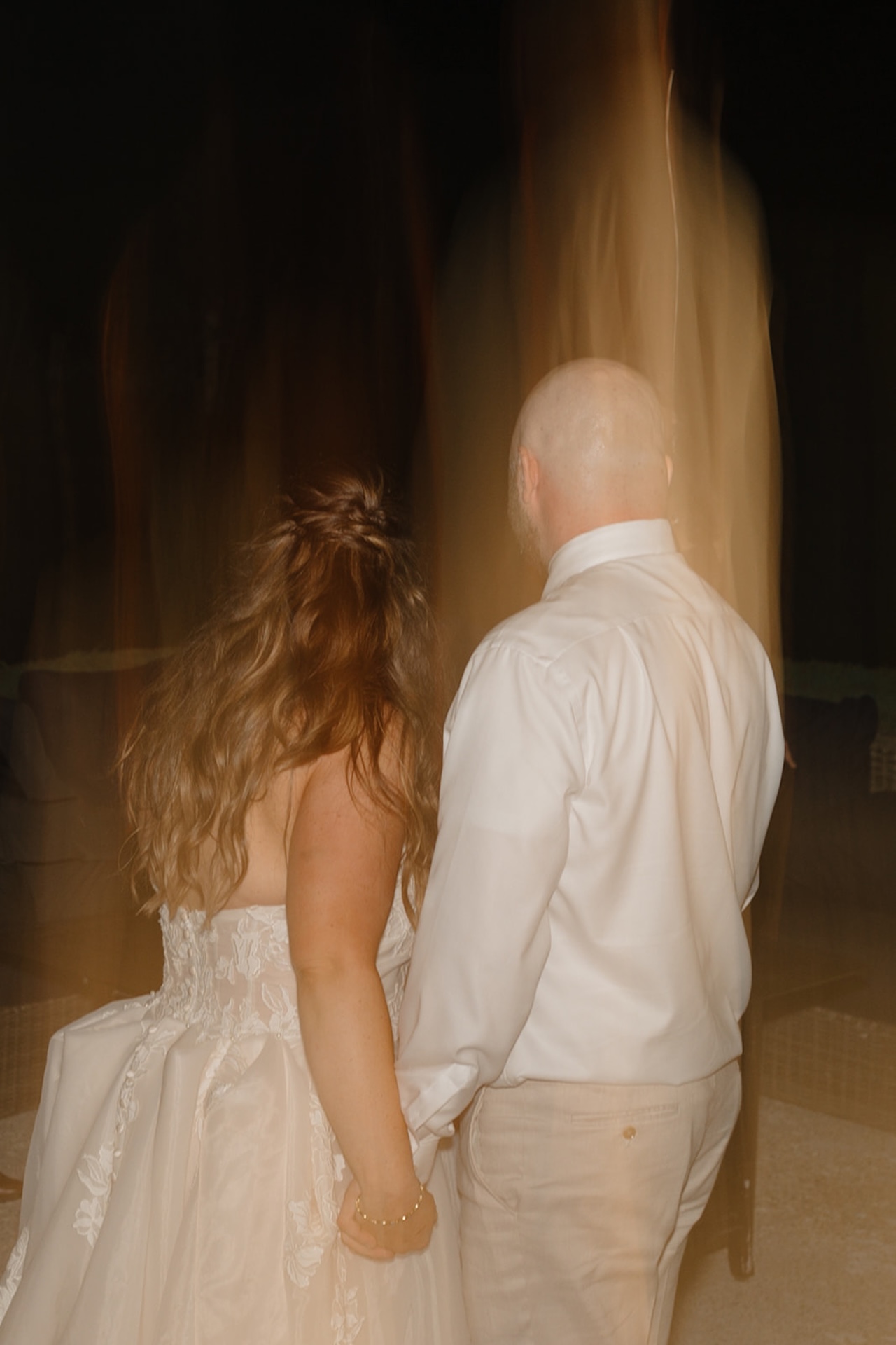 A motion blur photo of the bride and groom holding hands and walking away from the camera.