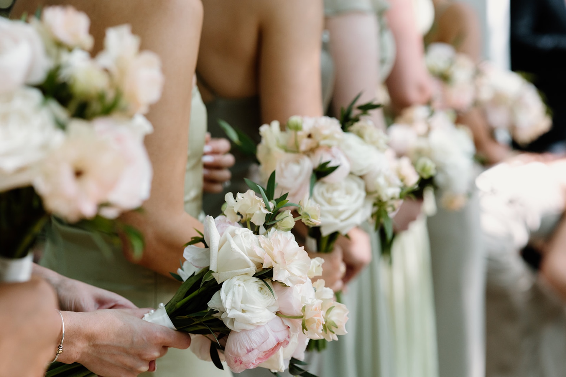 A detail photo of bridesmaids in green dresses holding colorful wedding bouquets for colorful wedding inspiration.