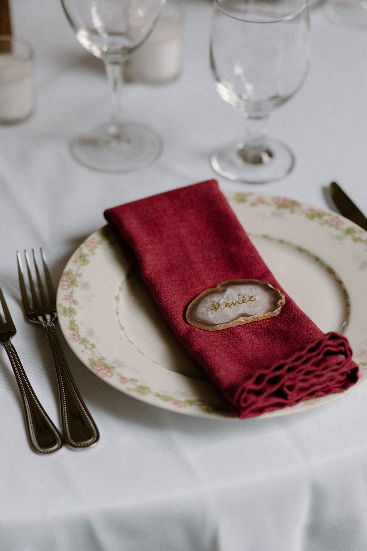 A simple wedding reception tablescape with a floral plate and bright red napkin.