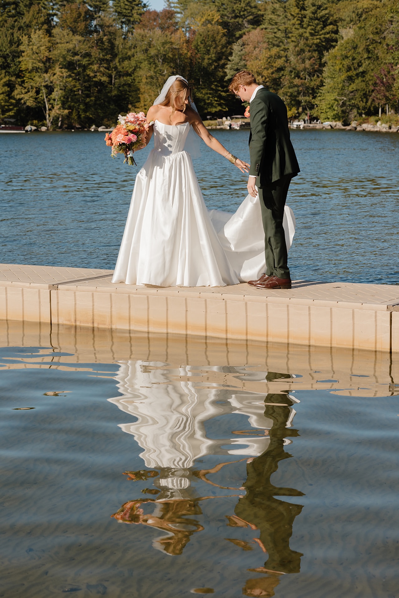 Newlyweds walking together on a dock during bride and groom portraits outdoors