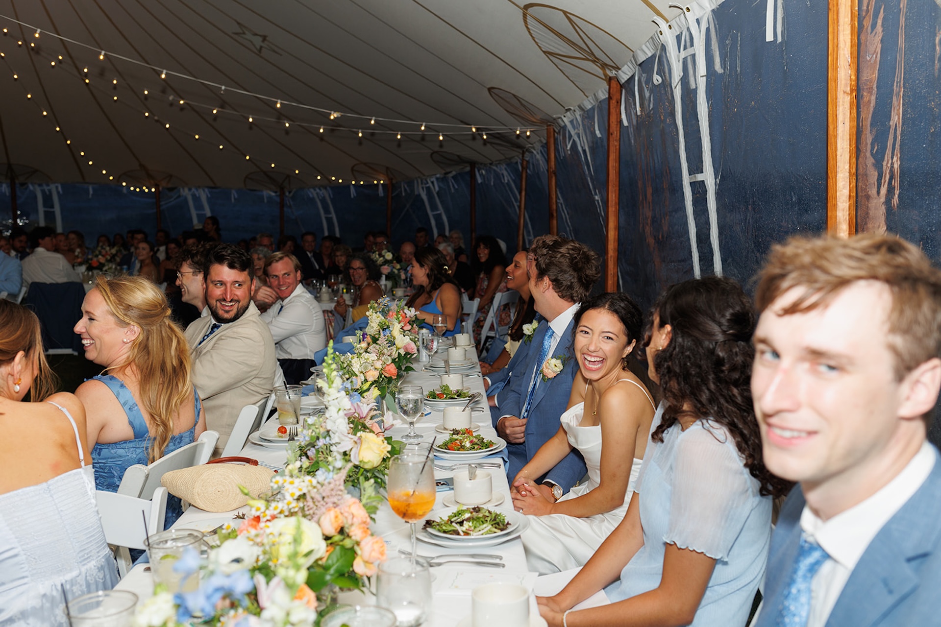 Weddings gueses in blue and white sitting at the wedding reception tables with colorful florals decorating the tables. Perfect inspiration for colorful wedding details.