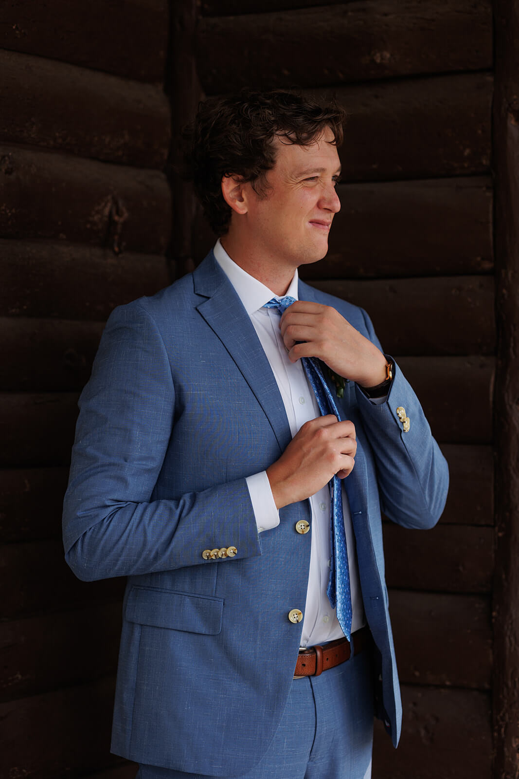 Groom adjusting his tie before a coastal Maine micro wedding inside a rustic cabin wedding venue.