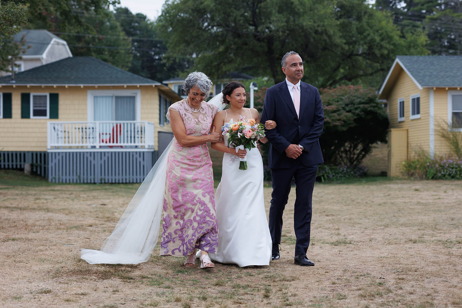 Bride walking down the aisle with her parents during a coastal Maine micro wedding ceremony.