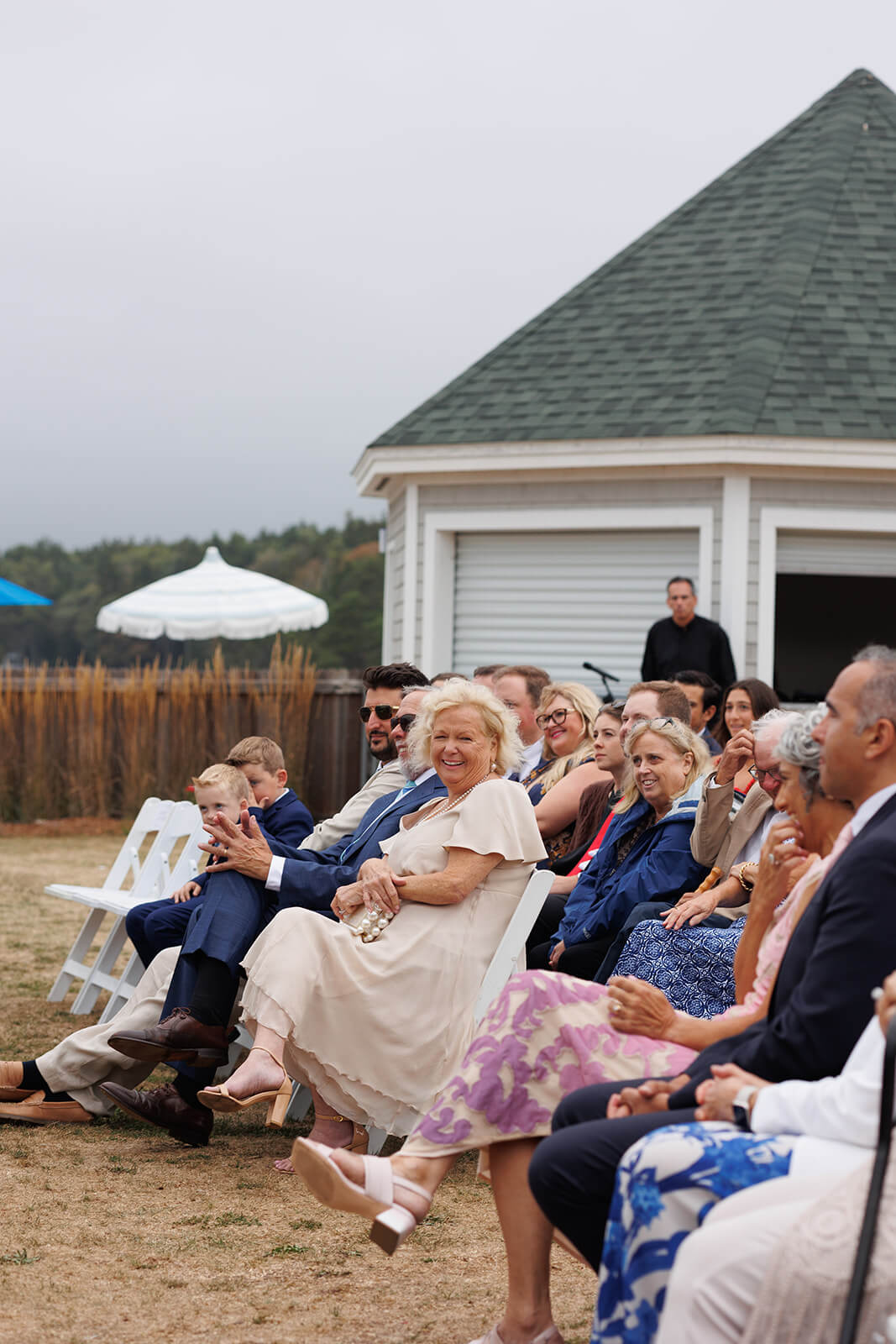 Wedding guests holding umbrellas during a rainy coastal Maine micro wedding ceremony.