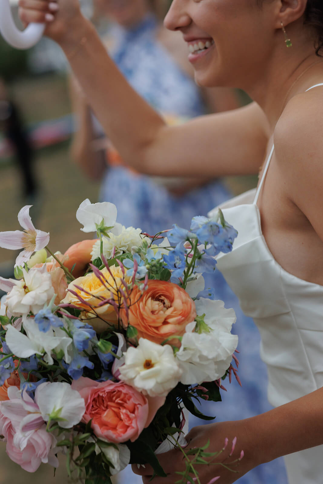 Bride holding a colorful bouquet and smiling during her coastal Maine micro wedding reception.