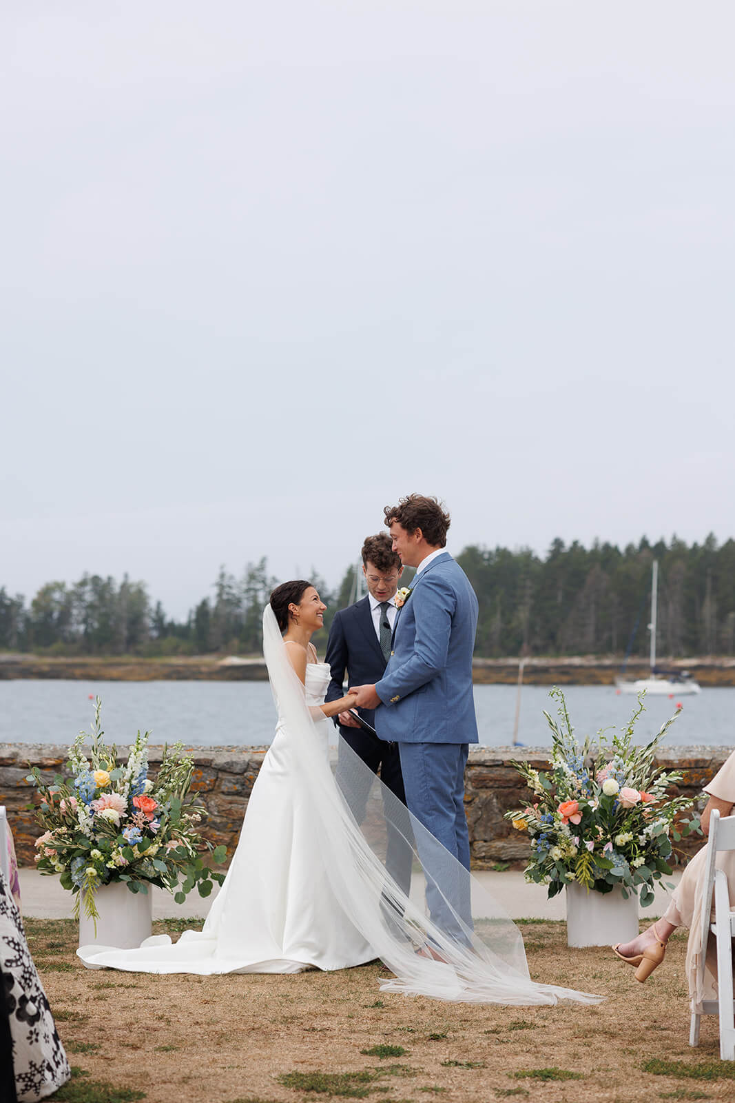 Bride and groom holding hands during their intimate coastal Maine wedding ceremony overlooking the harbor.