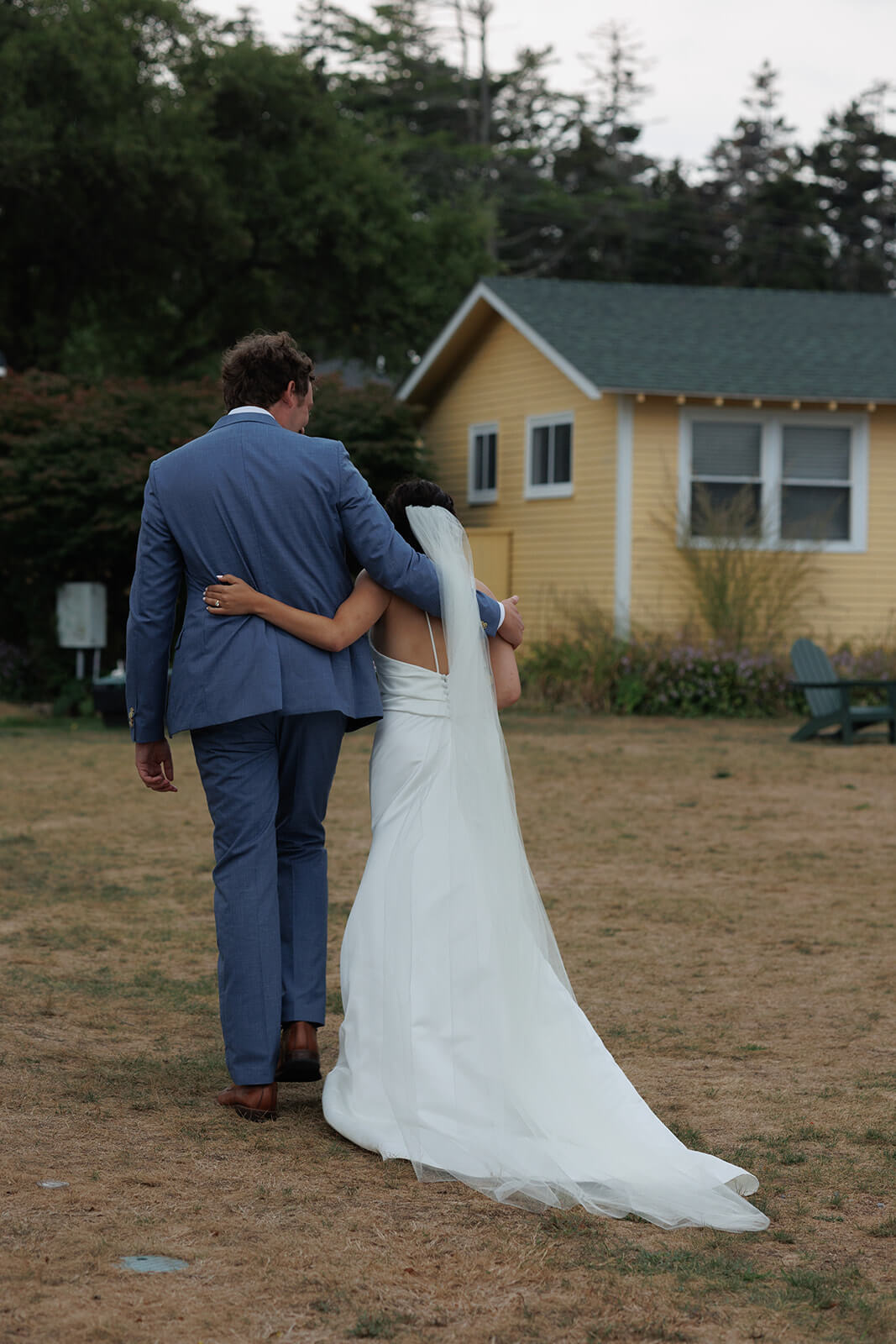 Newly married couple walking arm in arm through Sebasco Harbor Resort after their coastal Maine wedding ceremony.