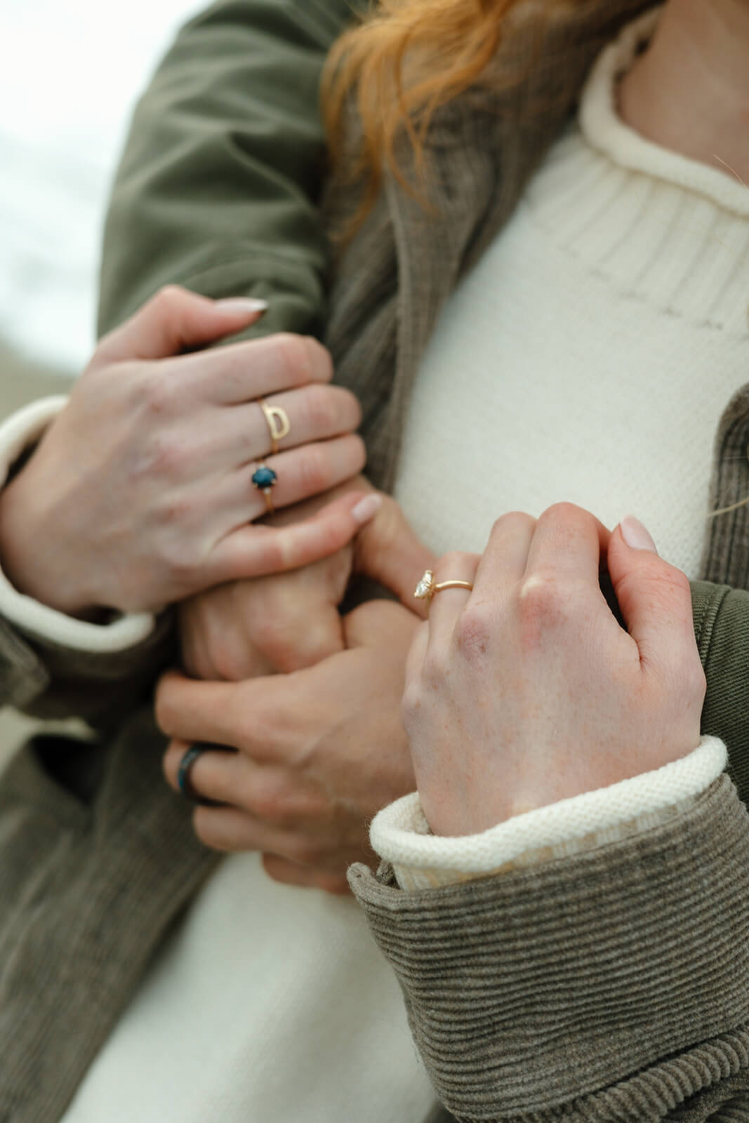 Detail shot from a coastal engagement photoshoot featuring intertwined hands and engagement rings