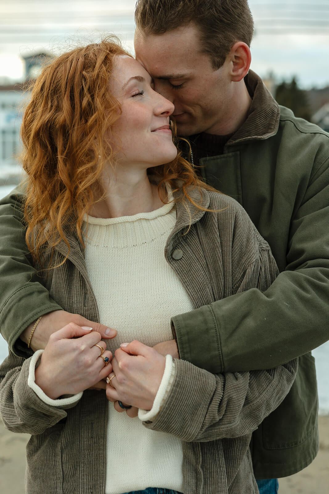 Cozy engagement photoshoot portrait of a couple embracing on the beach in Maine at sunset