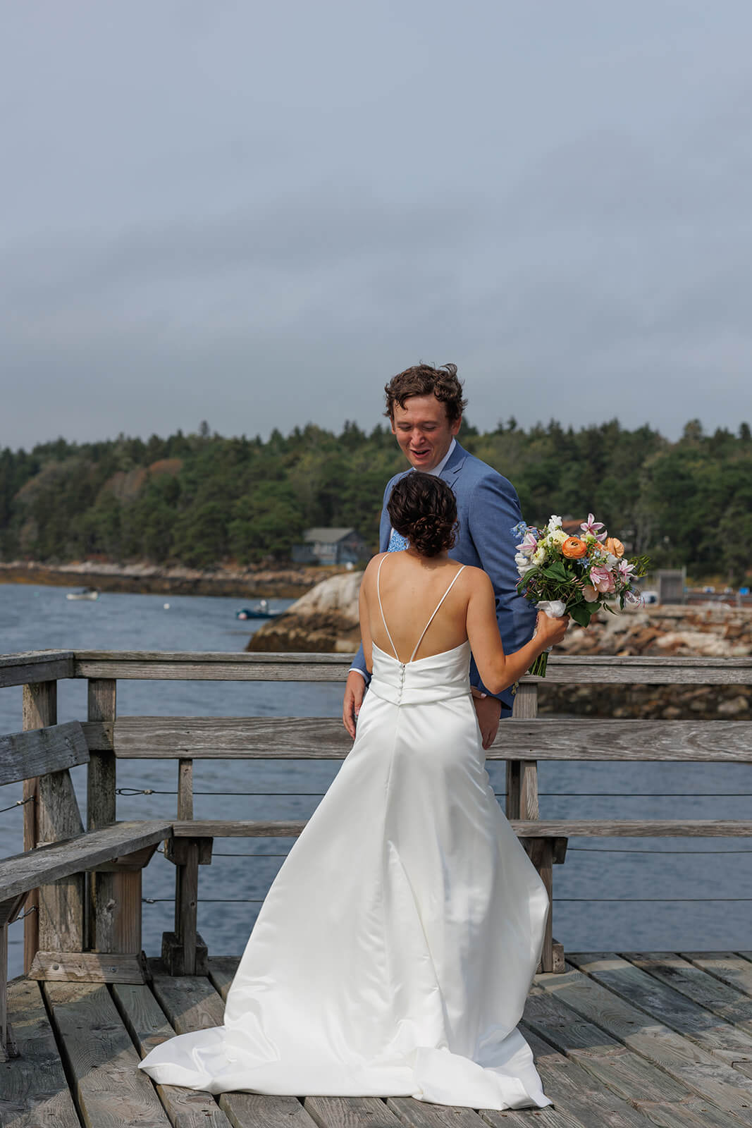 Newly married couple embracing on a wooden dock during their coastal Maine micro wedding portraits.