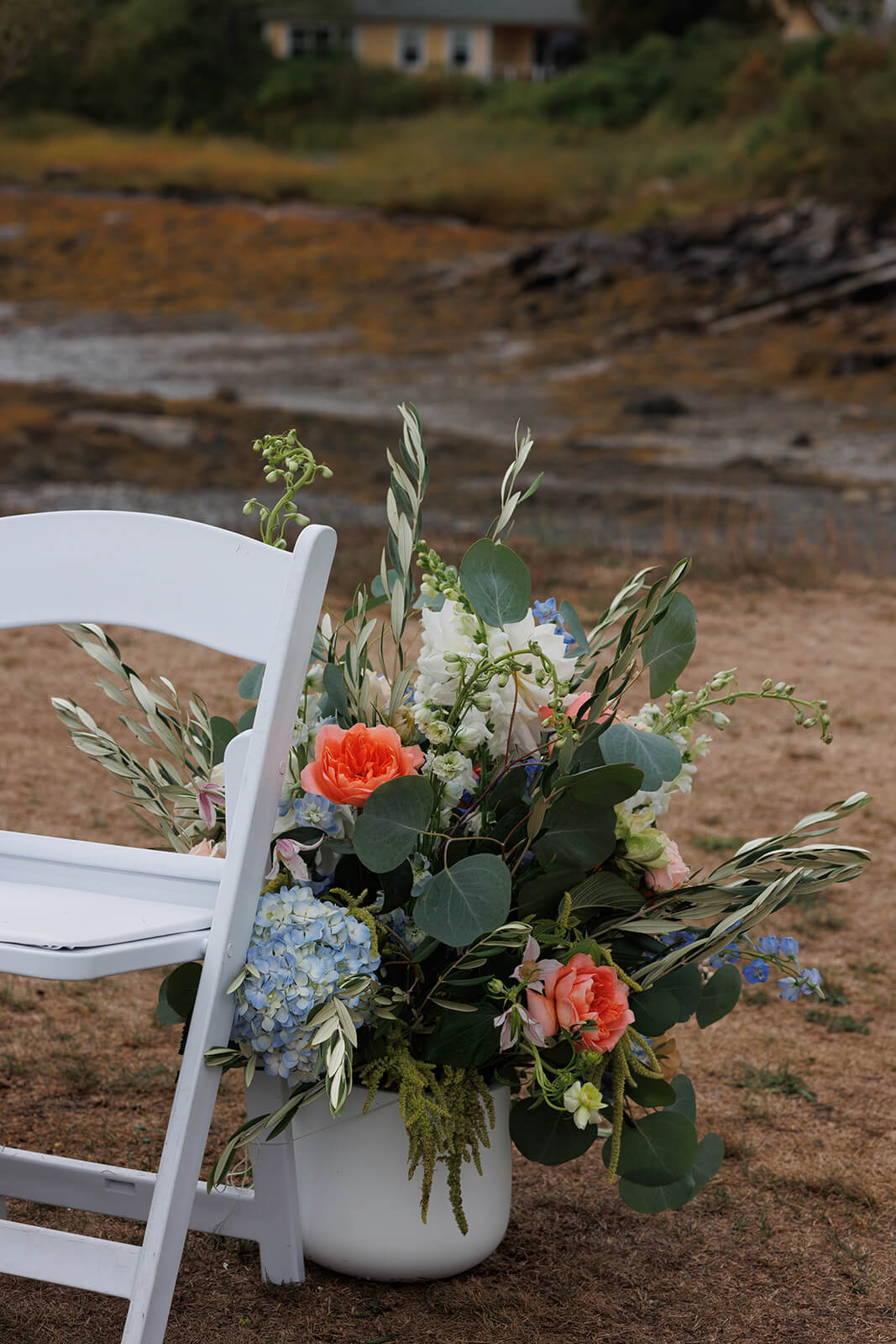Colorful floral arrangement beside white ceremony chairs during a coastal Maine micro wedding at Sebasco Harbor Resort.