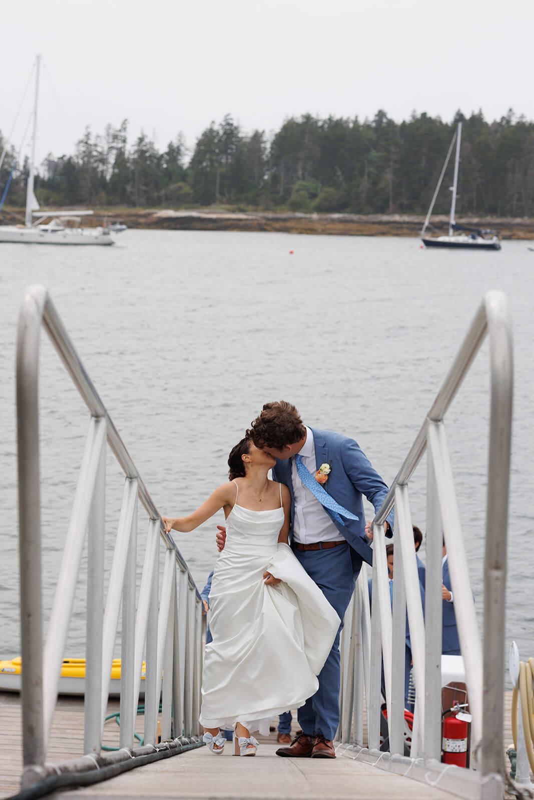 Bride and groom kissing on a dock during their waterfront micro wedding in coastal Maine.