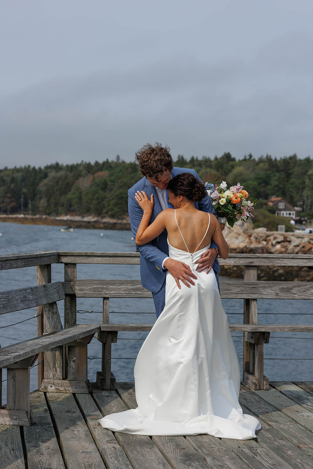 Bride and groom holding each other on a waterfront deck during a Sebasco Harbor Resort wedding in Maine.