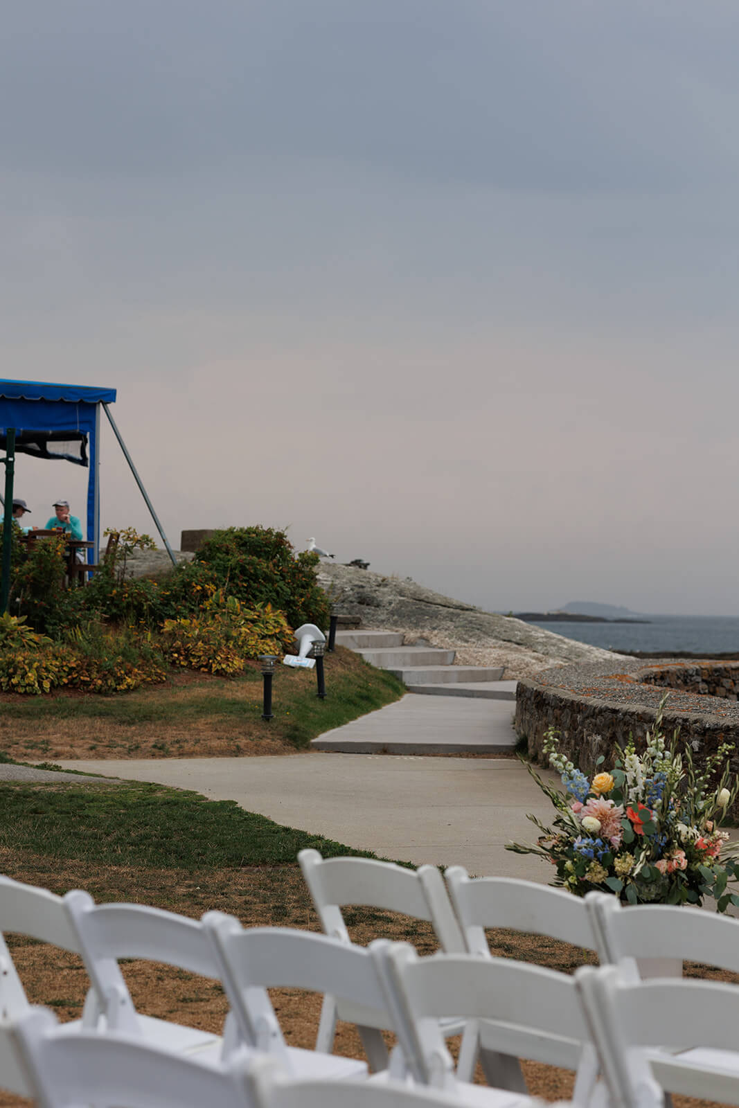 Waterfront ceremony setup at Sebasco Harbor Resort with white chairs and pastel floral arrangements along the Maine coast.