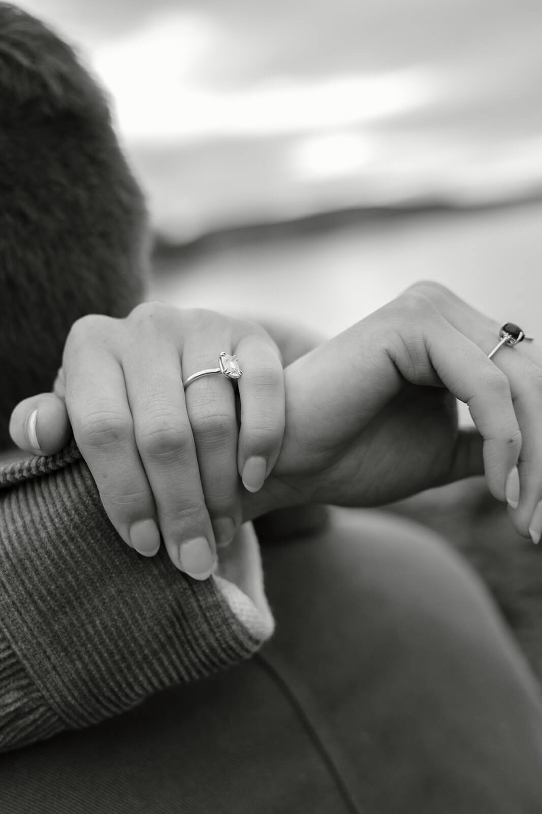 Black and white close-up of engagement ring details during an intimate beach engagement photoshoot