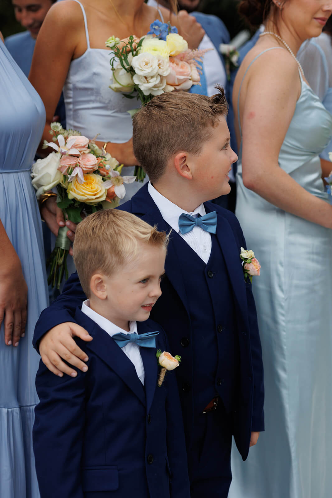 Young ring bearers in blue suits standing with the wedding party during a coastal Maine wedding ceremony.