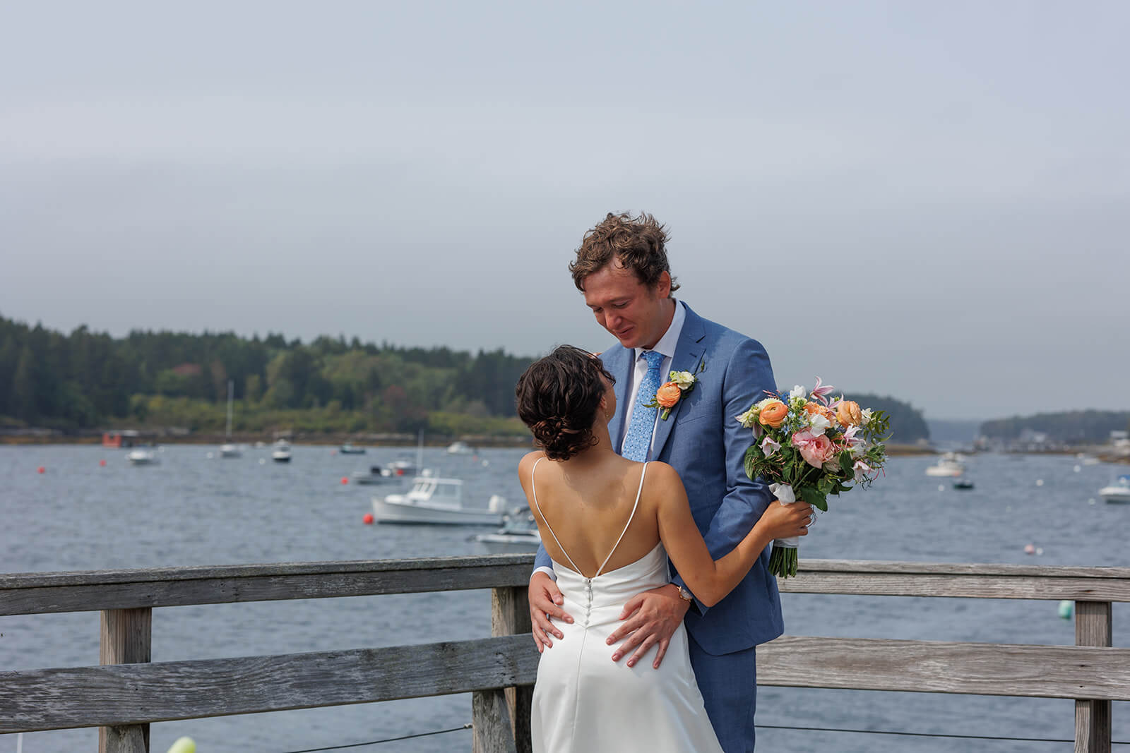Intimate waterfront wedding portrait of bride and groom overlooking the harbor during a coastal Maine micro wedding.