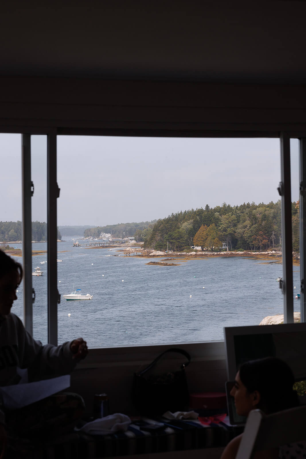 Coastal Maine wedding morning view overlooking the ocean and pine-covered shoreline from inside the getting ready space.