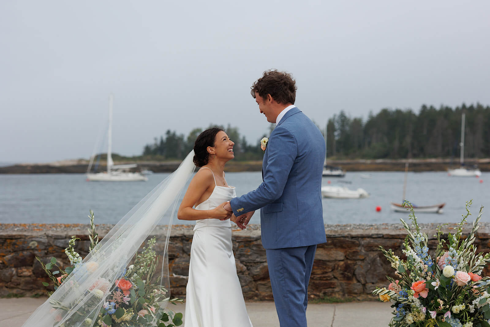 Bride and groom exchanging smiles during their waterfront wedding ceremony in Maine.