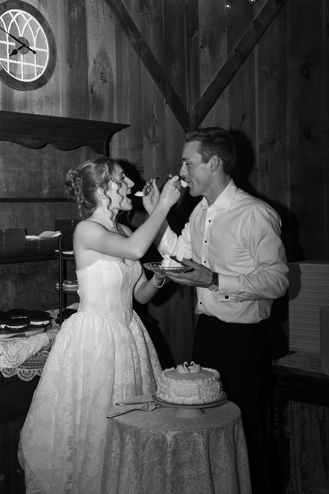 Black-and-white photo of the bride feeding the groom a bite of wedding cake.
